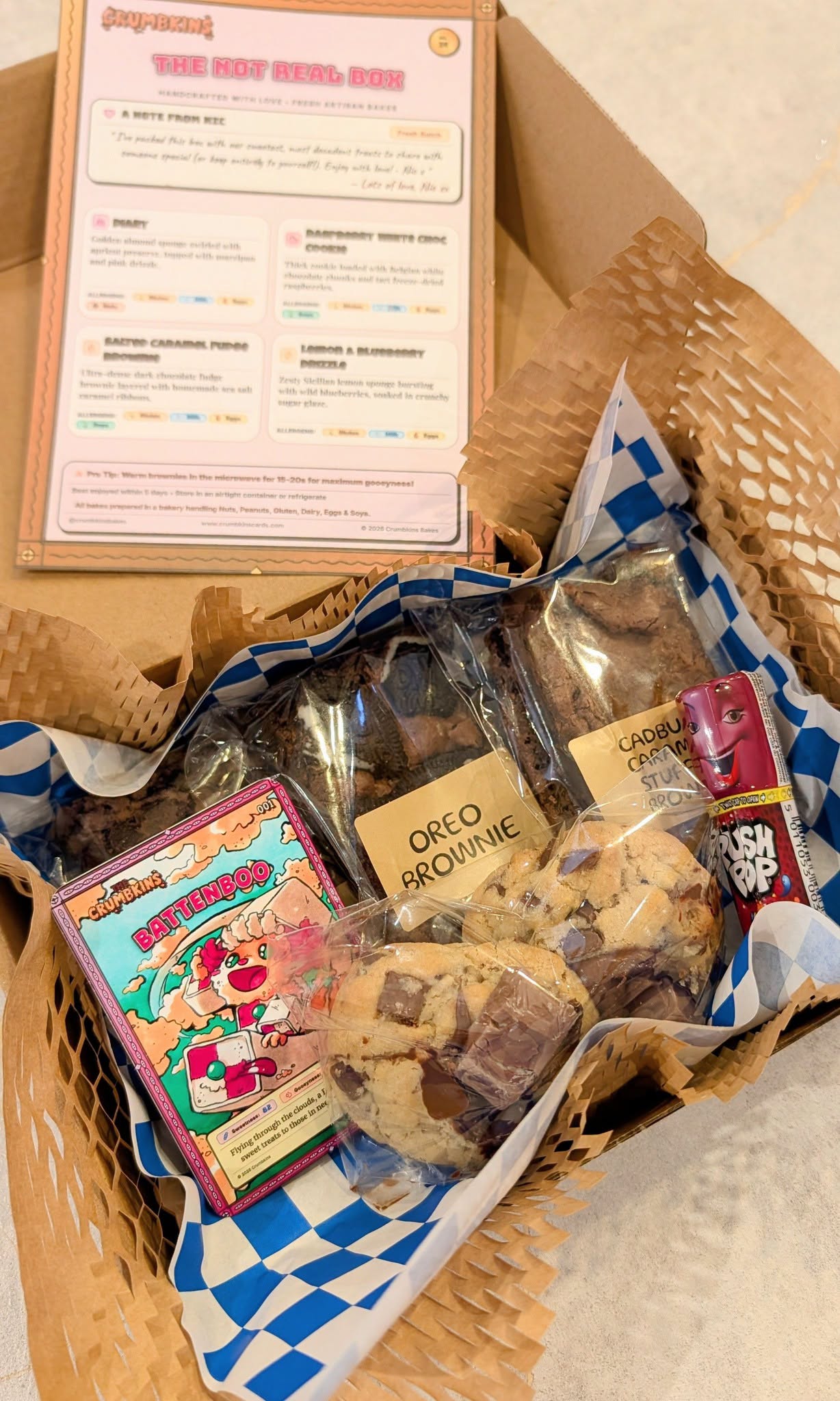 An open Crumbkins box packed with four bakes, a Battenboo collectable card, a menu card and a little sweet surprise.